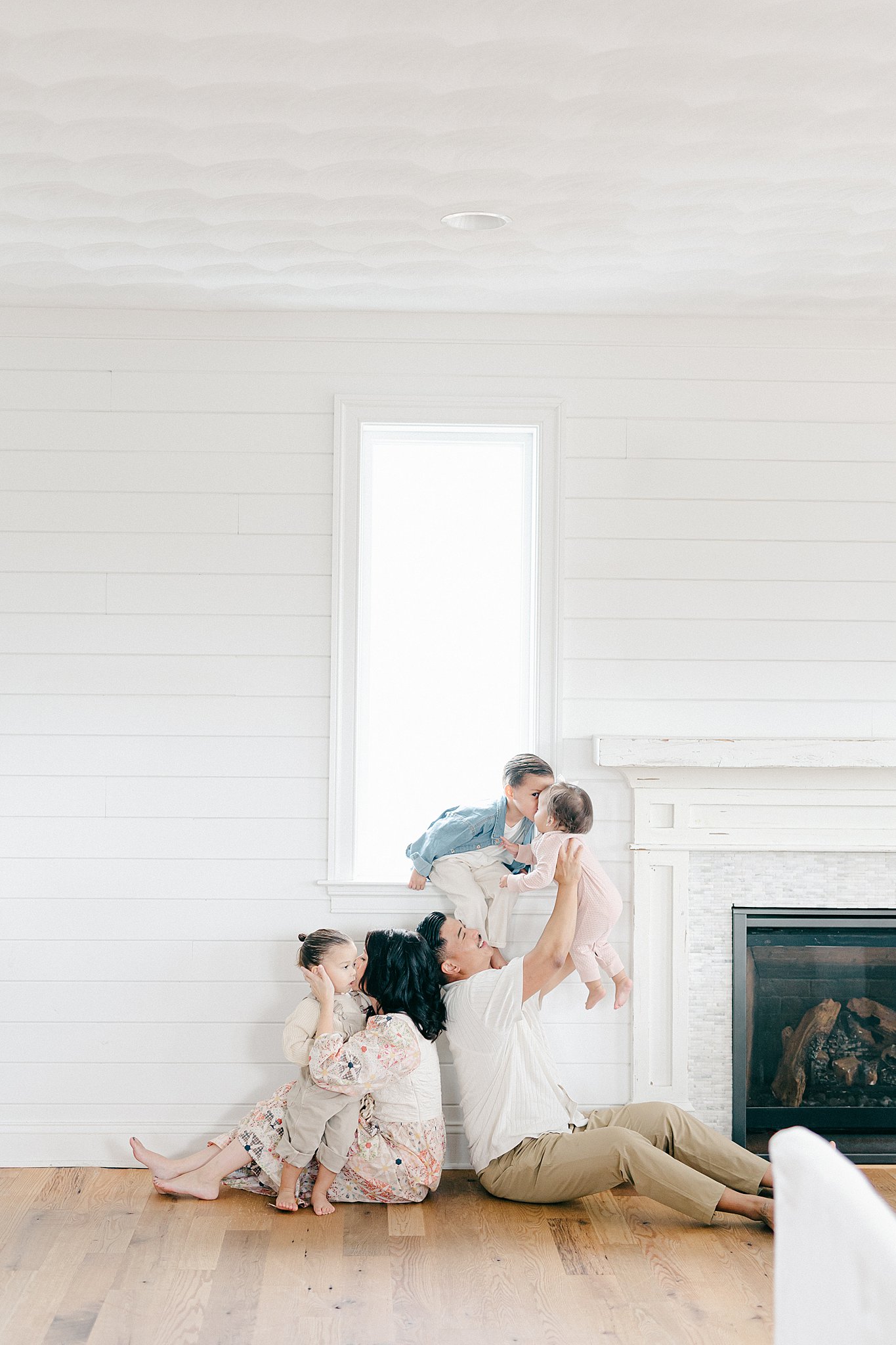 Family cuddling in their home by the fireplace during a lifestyle family photo session at their home in jupiter, florida