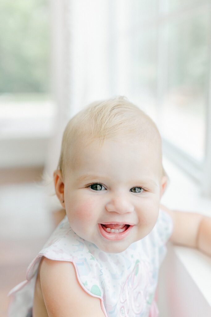 Close-up of smiling baby girl in natural light during an in-home session by a newborn photographer in Port Saint Lucie offering a stress-free experience for families.