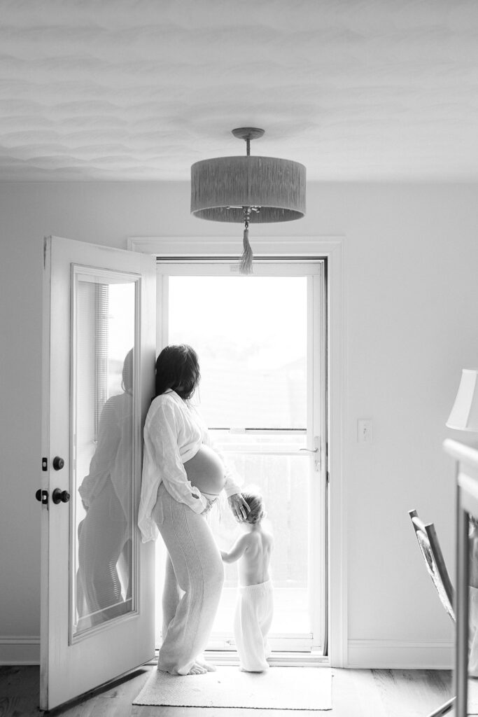 Natural light maternity moment with toddler and expectant mother near doorway — captured by a maternity photographer in Port Saint Lucie offering styling and wardrobe support.