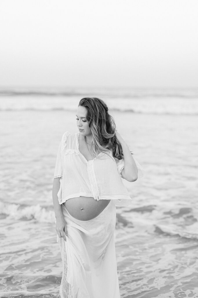 Elegant black-and-white maternity photo in the ocean waves, styled and captured by a luxury maternity photographer in Jupiter, Florida.