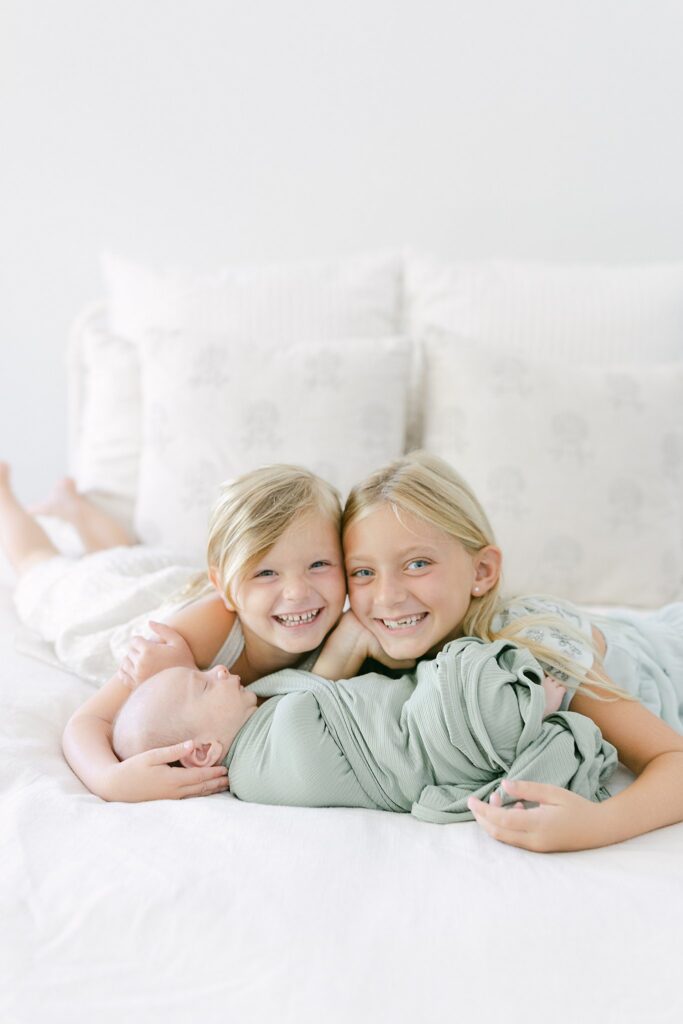 Siblings snuggling with their newborn baby brother — family portraits by a Palm Beach Gardens newborn photographer who offers wardrobe styling.
