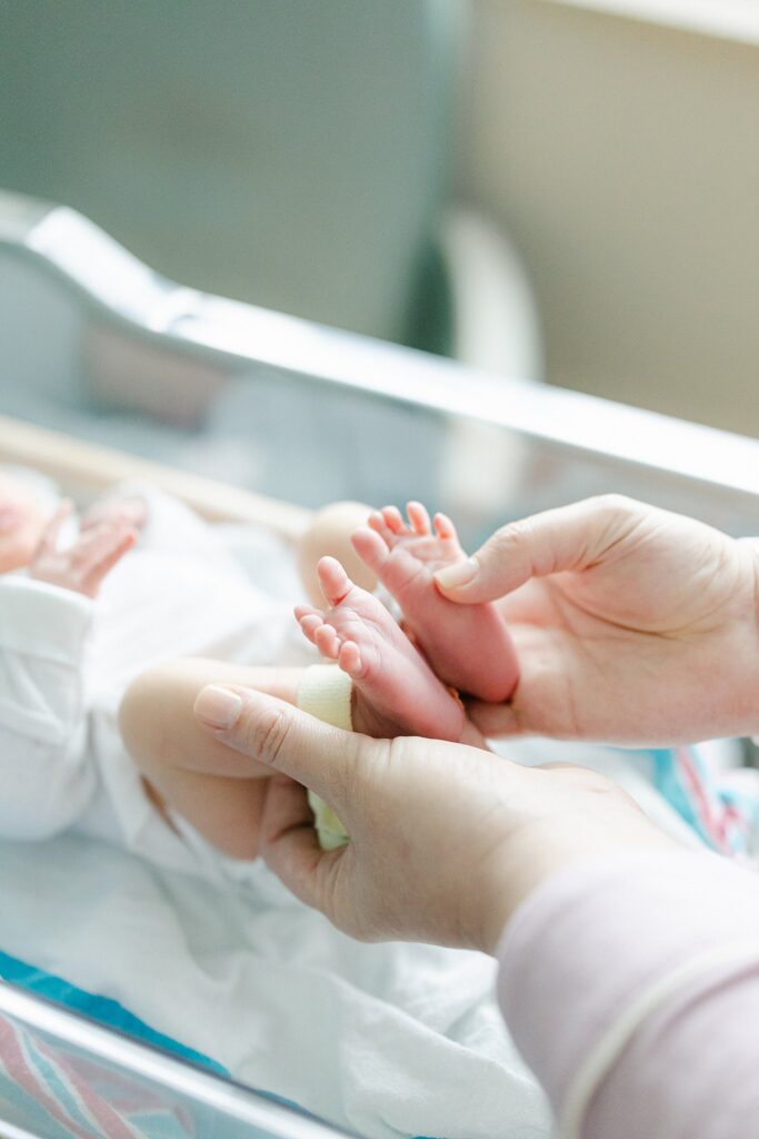 First moments captured in the hospital — newborn baby feet held gently, part of a stress-free newborn photography package in Port Saint Lucie, Florida.