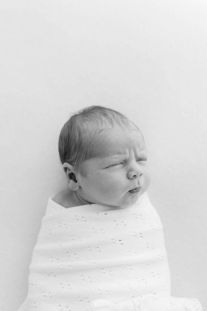 Minimalist newborn portrait on white bedding, styled and photographed by a stress-free newborn photographer in Port Saint Lucie.